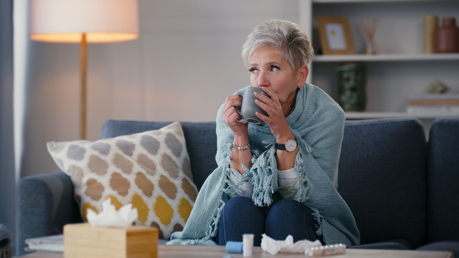 ill woman under blanket on sofa