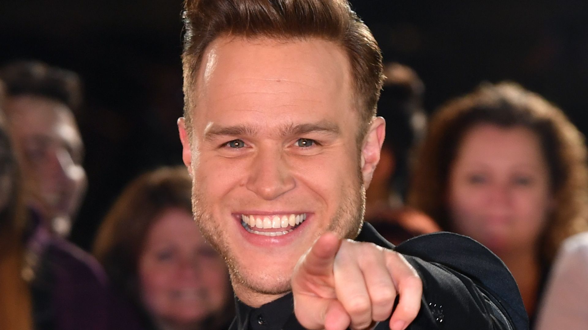 Olly Murs pointing at the camera in a black suit