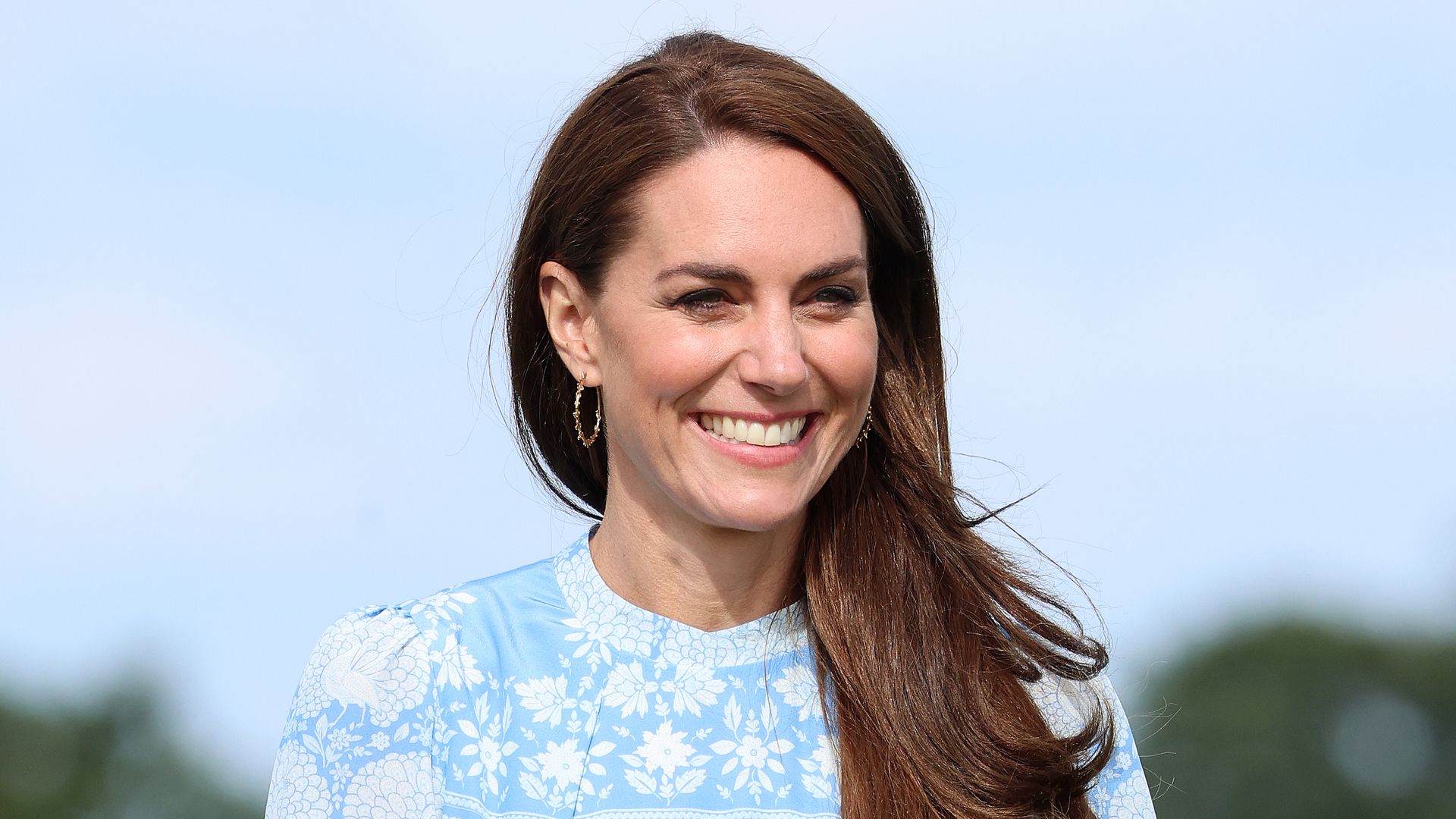 Kate Middleton smiling and wearing blue dress at charity polo match