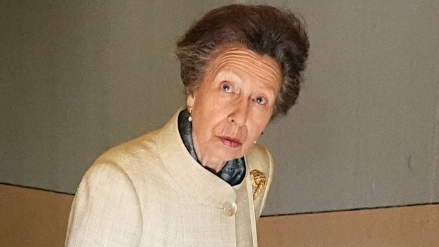 Princess Anne peering around look surprised in a smart cream coat