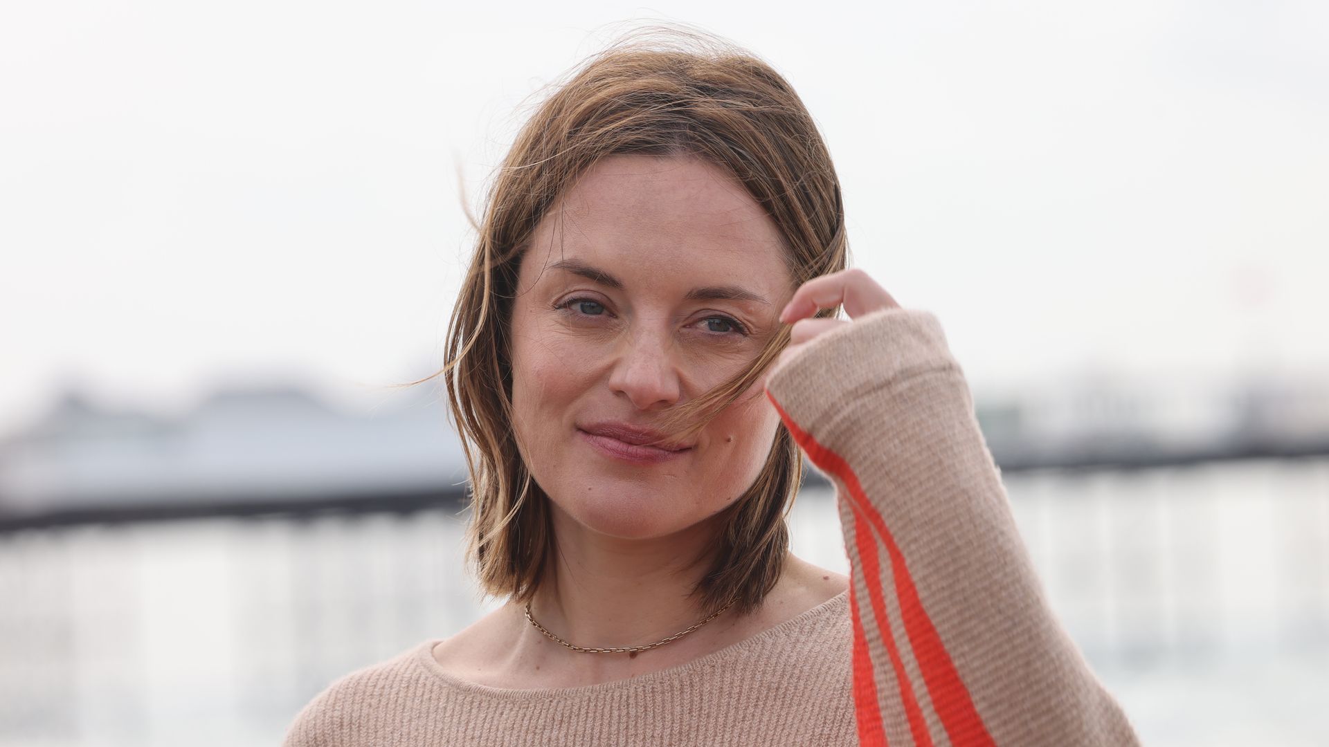 Woman standing in front of sea in orange striped jumper