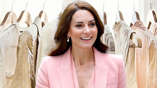 Kate Middleton in pink blazer with rail of clothes backdrop