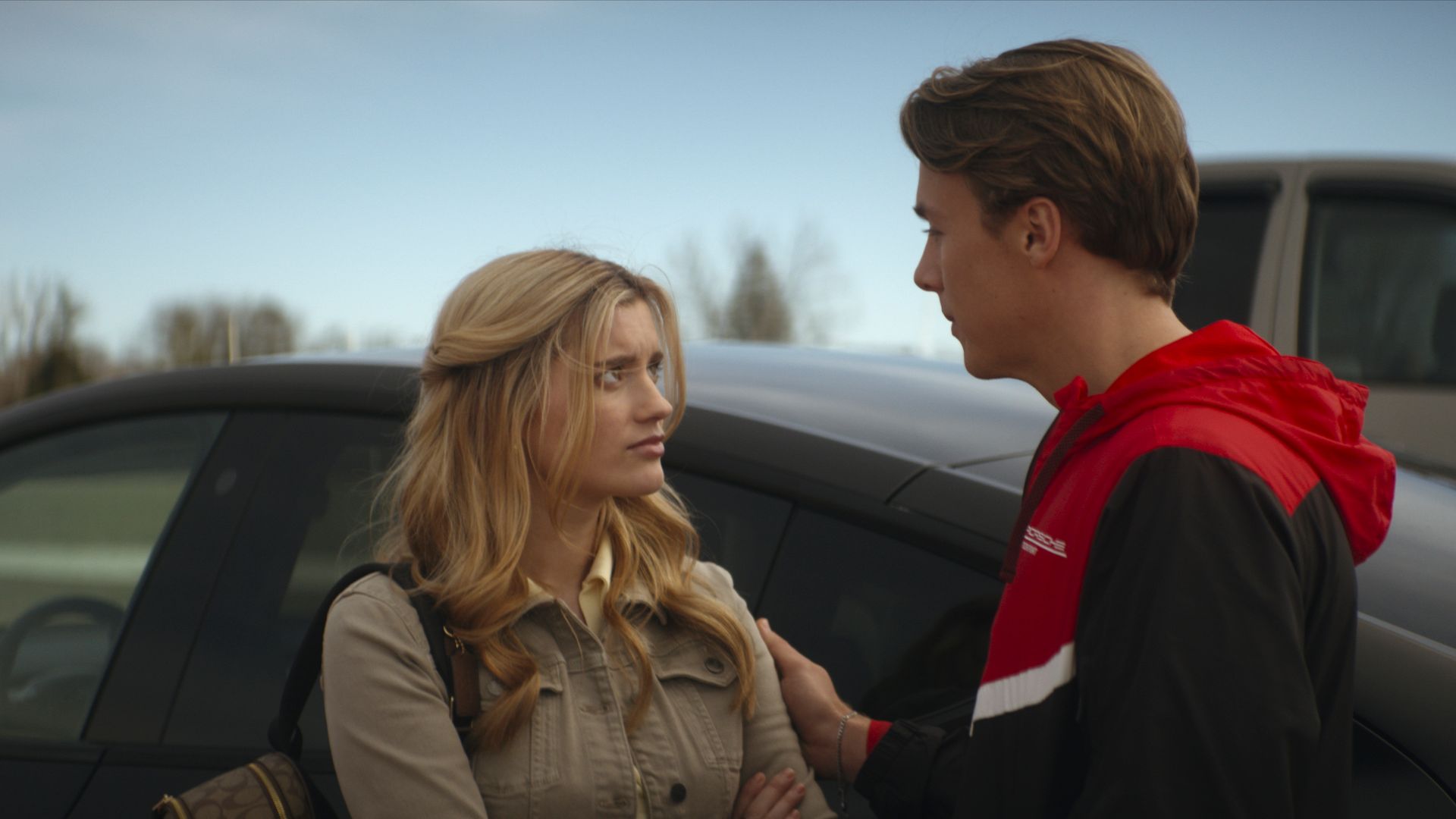 teenage girl and boy standing by car