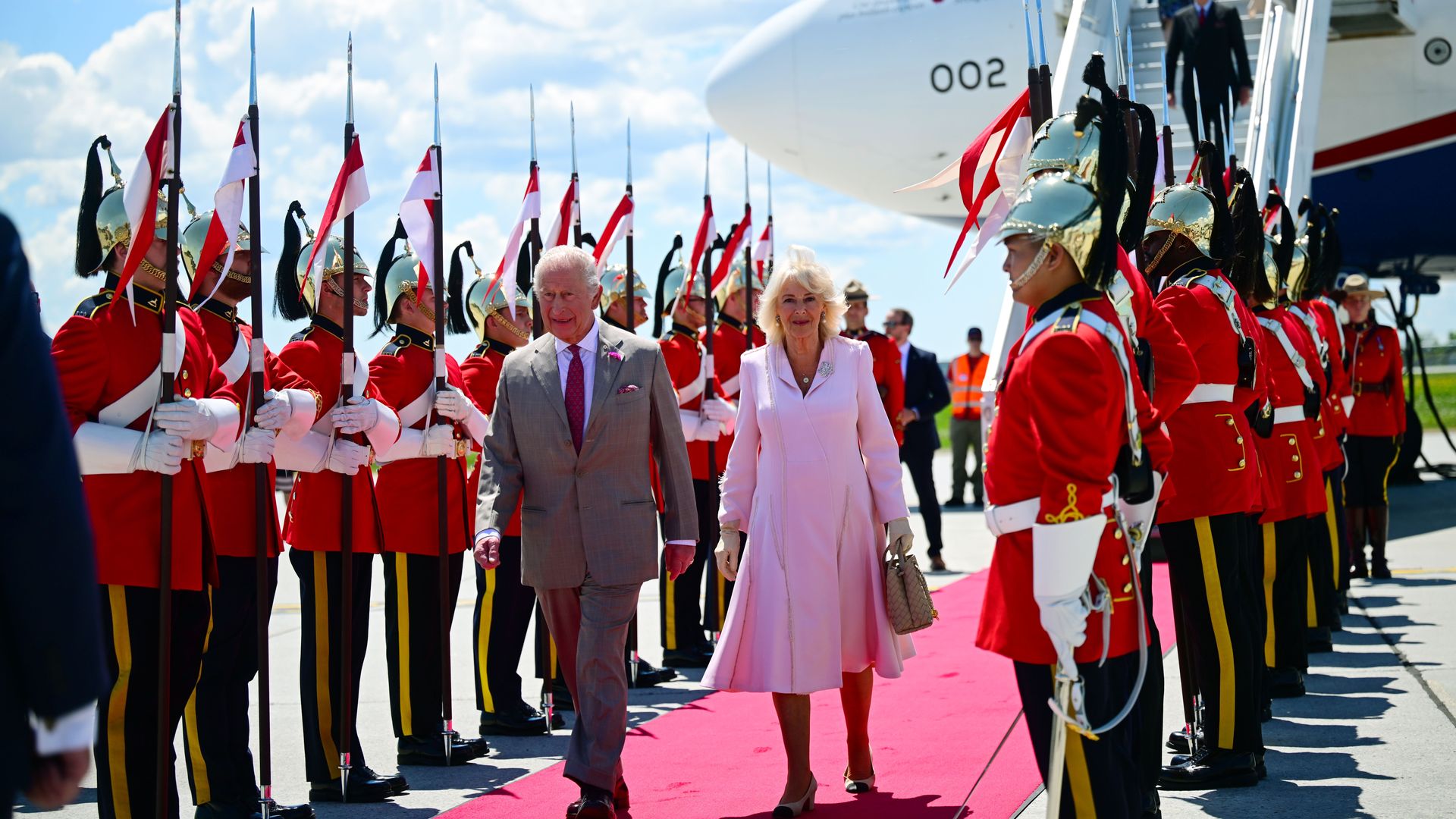 King Charles and Queen Camilla walking past guards