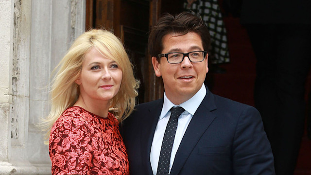 Kitty McIntyre in a red dress standing with Michael McIntyre in a black suit