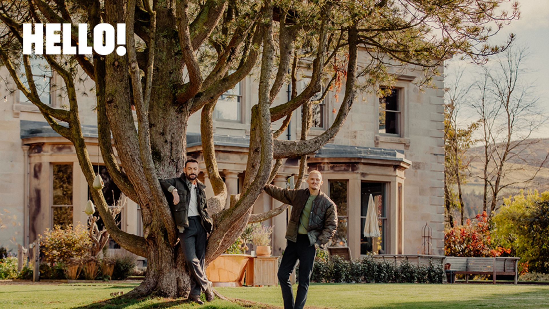 two man posing in a tree outside of their home