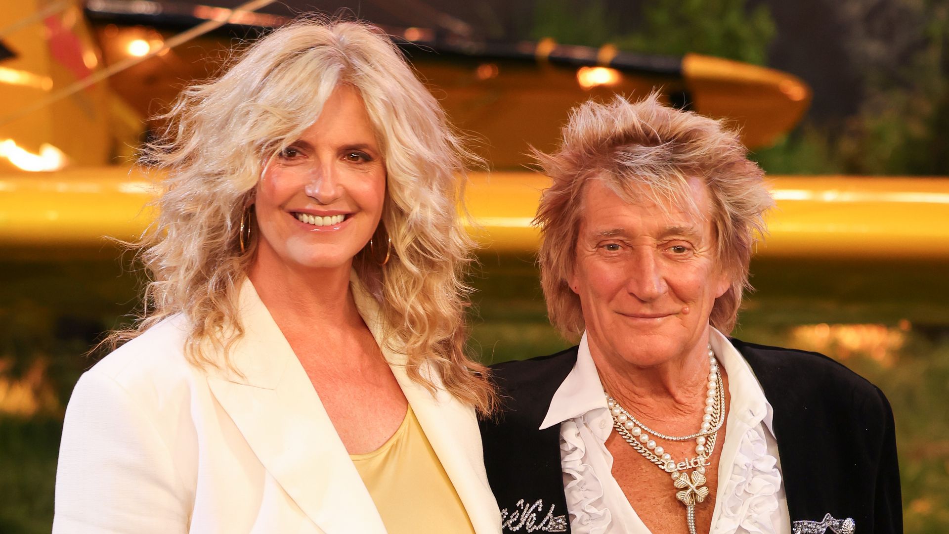 Penny Lancaster in a yellow dress and Rod Stewart in a frilly black suit