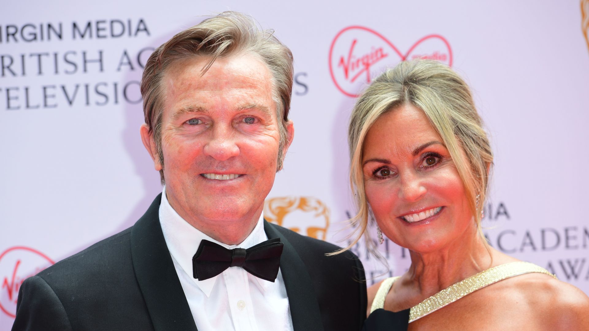 man and woman smiling for camera on red carpet