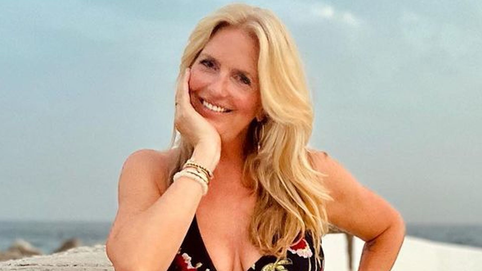 Rod Stewart wife Penny Lancaster wearing black and red floral dress with plunging neckline at seaside