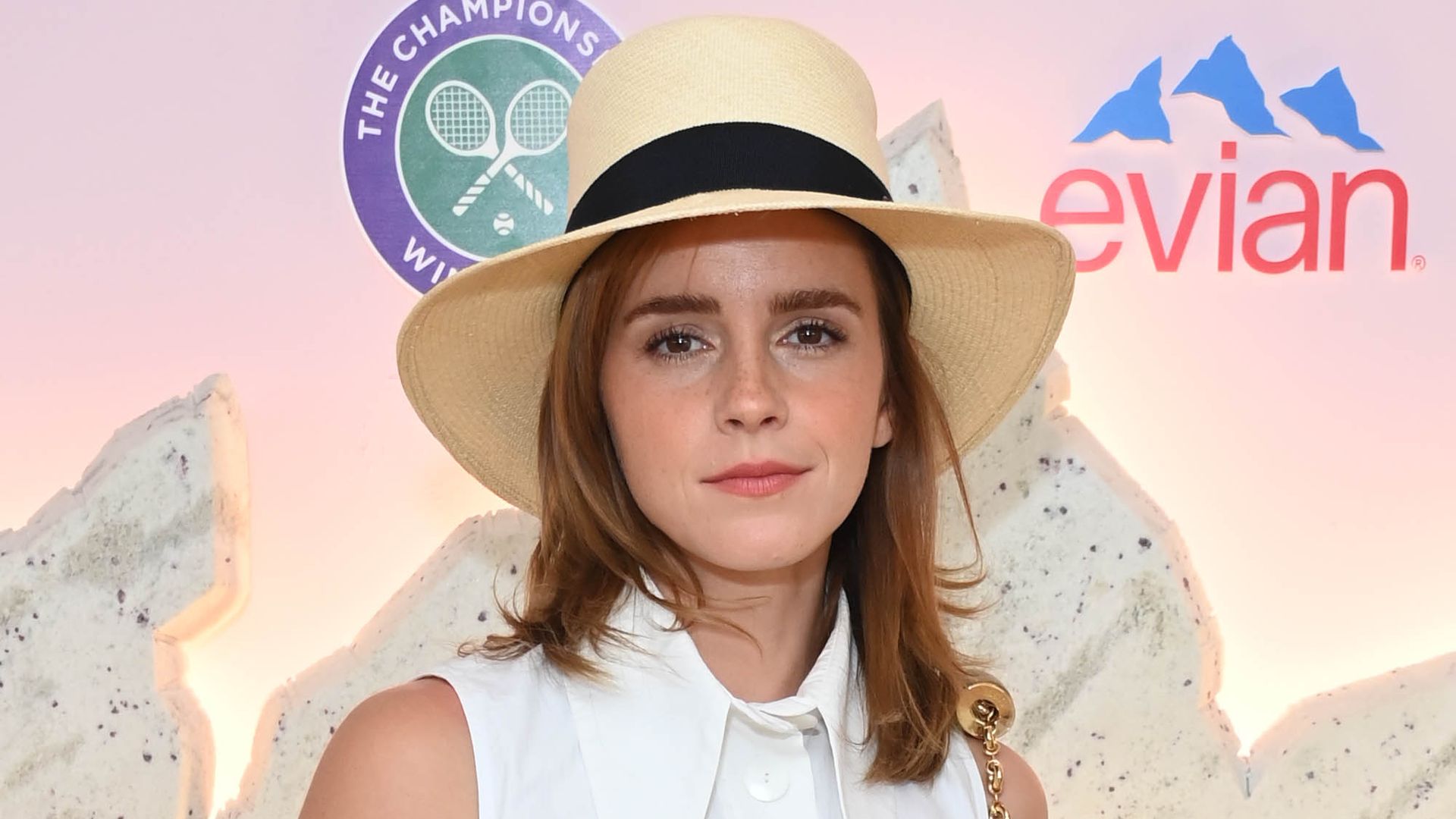 Emma Watson wearing a white sleeveless shirt with an oversized collar and pink trousers