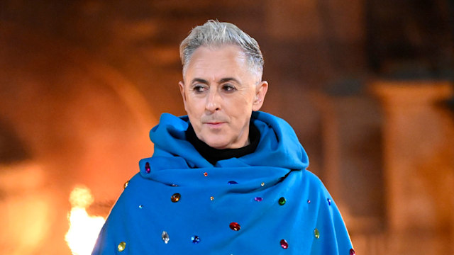 Alan Cumming in a blue cloak