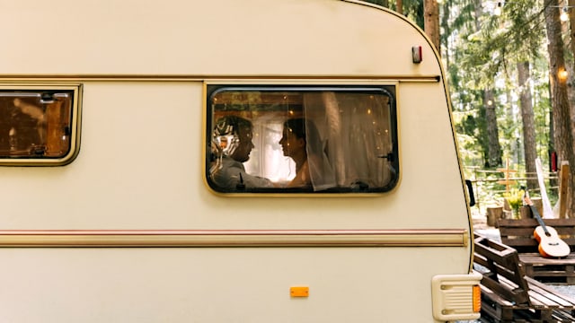 A young couple in love in a camper trailer on a summer day. Profile silhouettes.