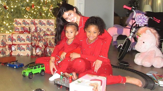 Kylie Jenner sitting on the floor with Stormi and Aire surrounded by Christmas presents