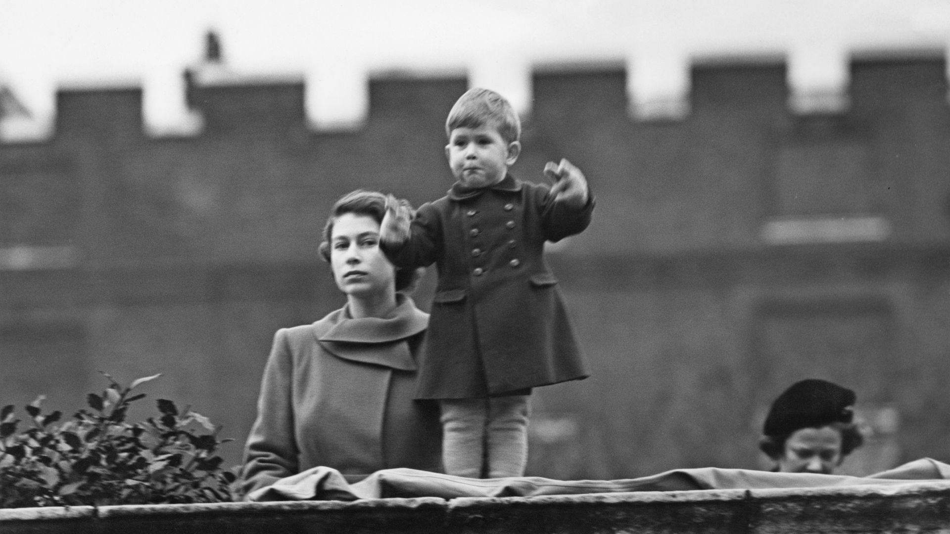 Prince Charles standing on the wall at Clarence House with Princess Elizabeth in 1950