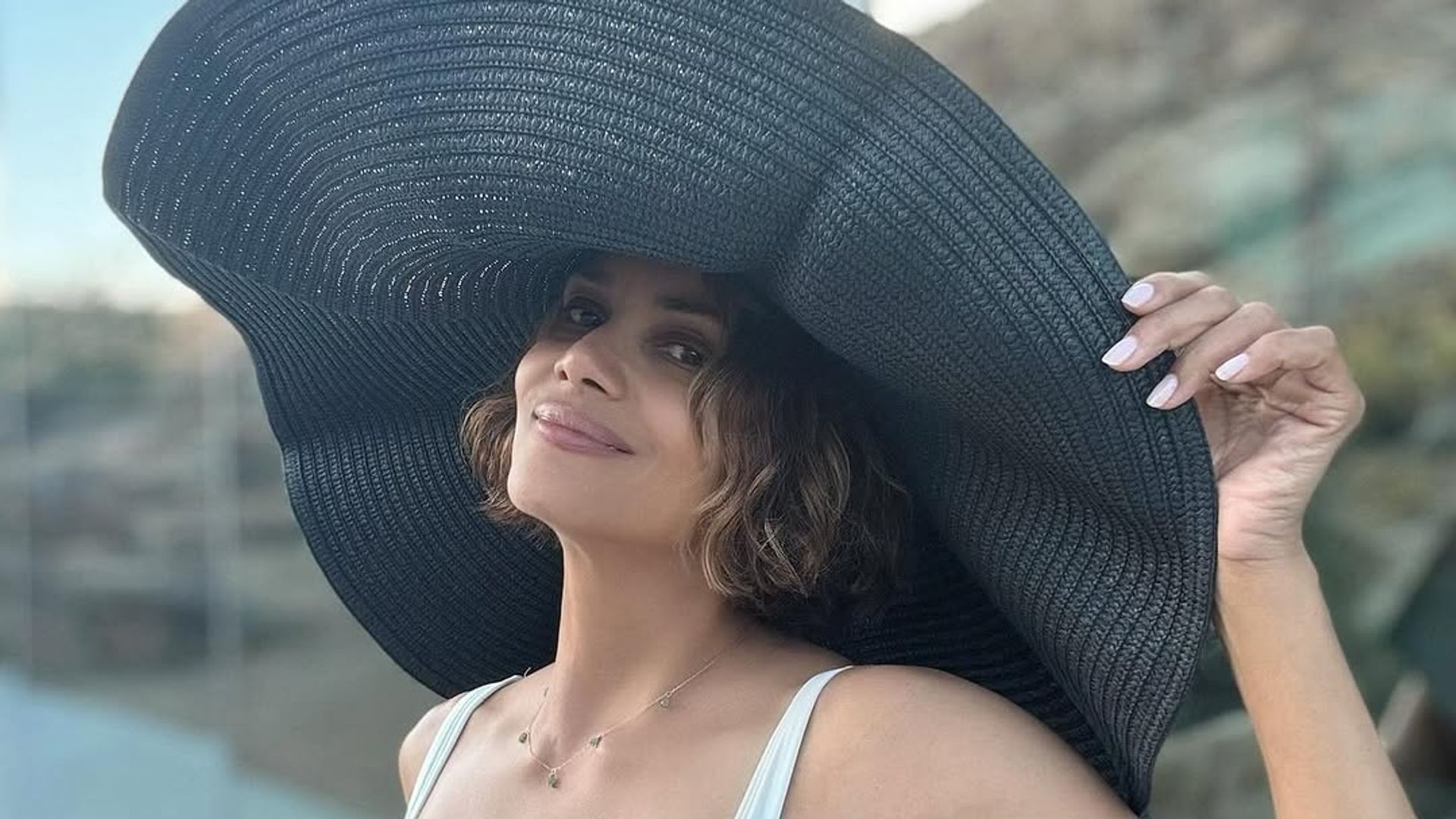 Halle Berry in black and white swimsuit with black sun hat