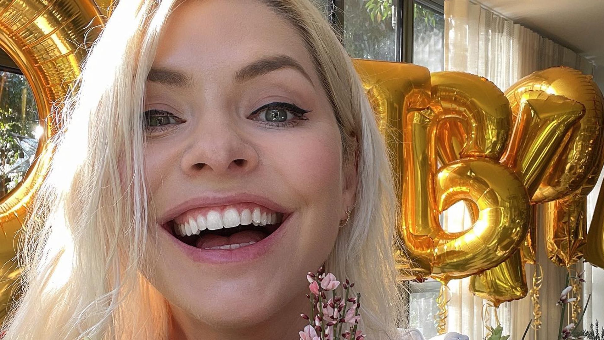 Holly Willoughby in pink with flowers and balloons in background