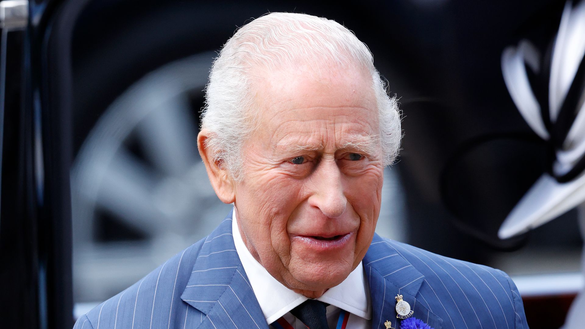 King Charles in a blue pinstripe suit with his medals