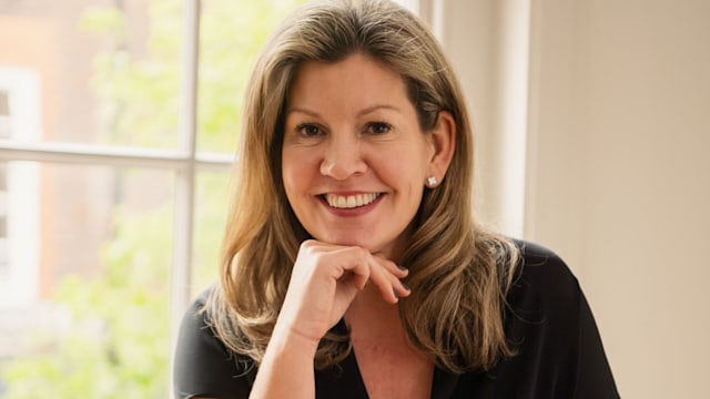 Woman smiling in smart clothes in front of a bright window