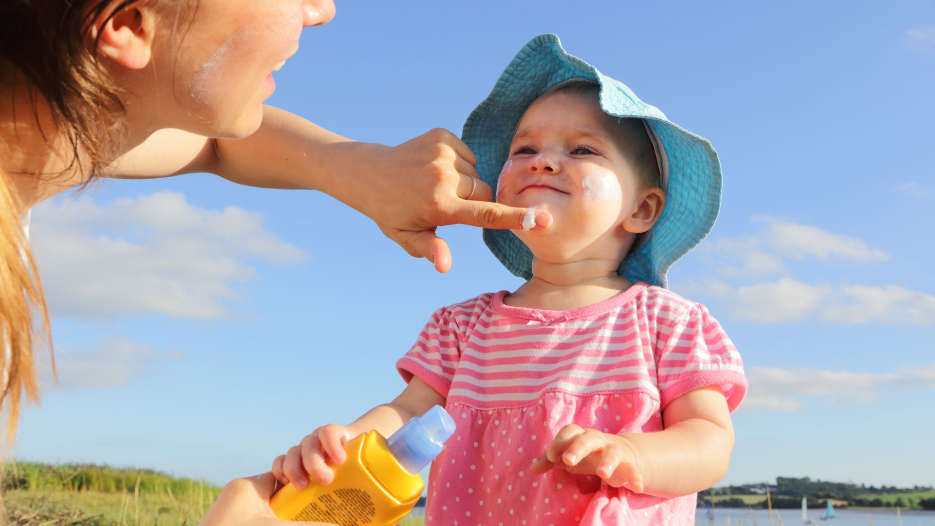 Mother putting sun cream on toddler girl