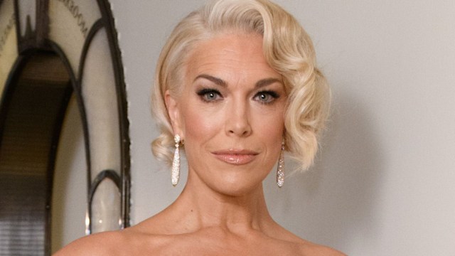 Hannah Waddingham in a gold dress leaning against a wall
