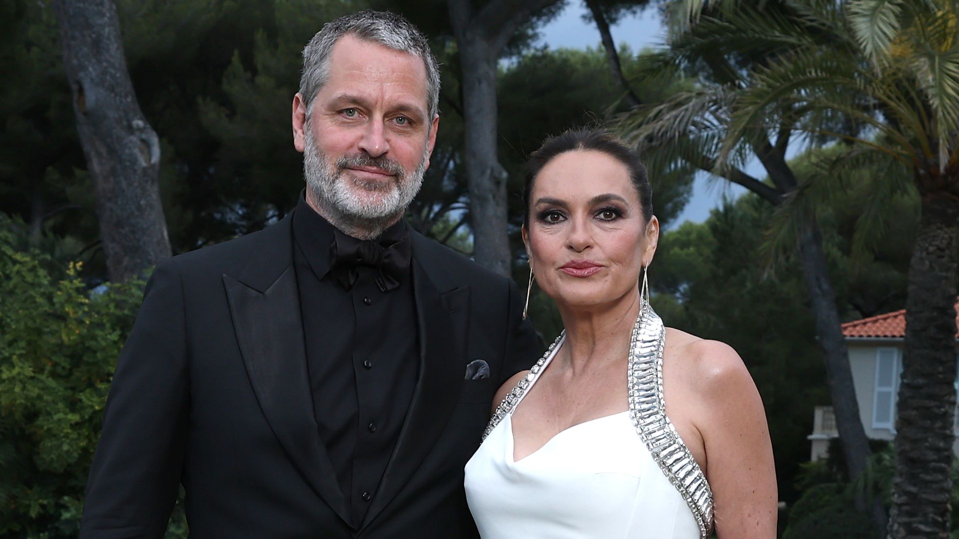 mariska hargitay in white dress with peter hermann in black suit standing on grass