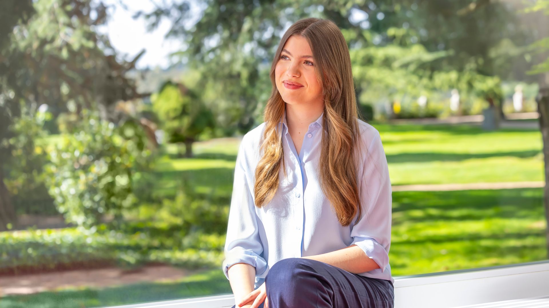 A girl with long hair looking towards the side whilst sitting