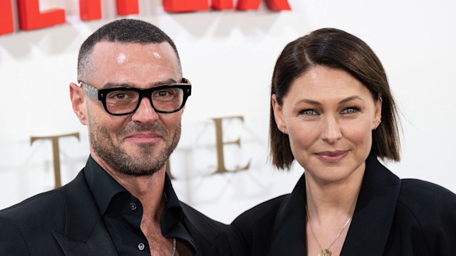 couple smiling for cameras on red carpet