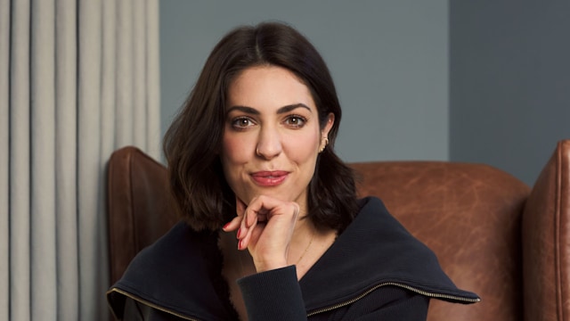 woman in jeans and a black top sitting in a comfy chair 