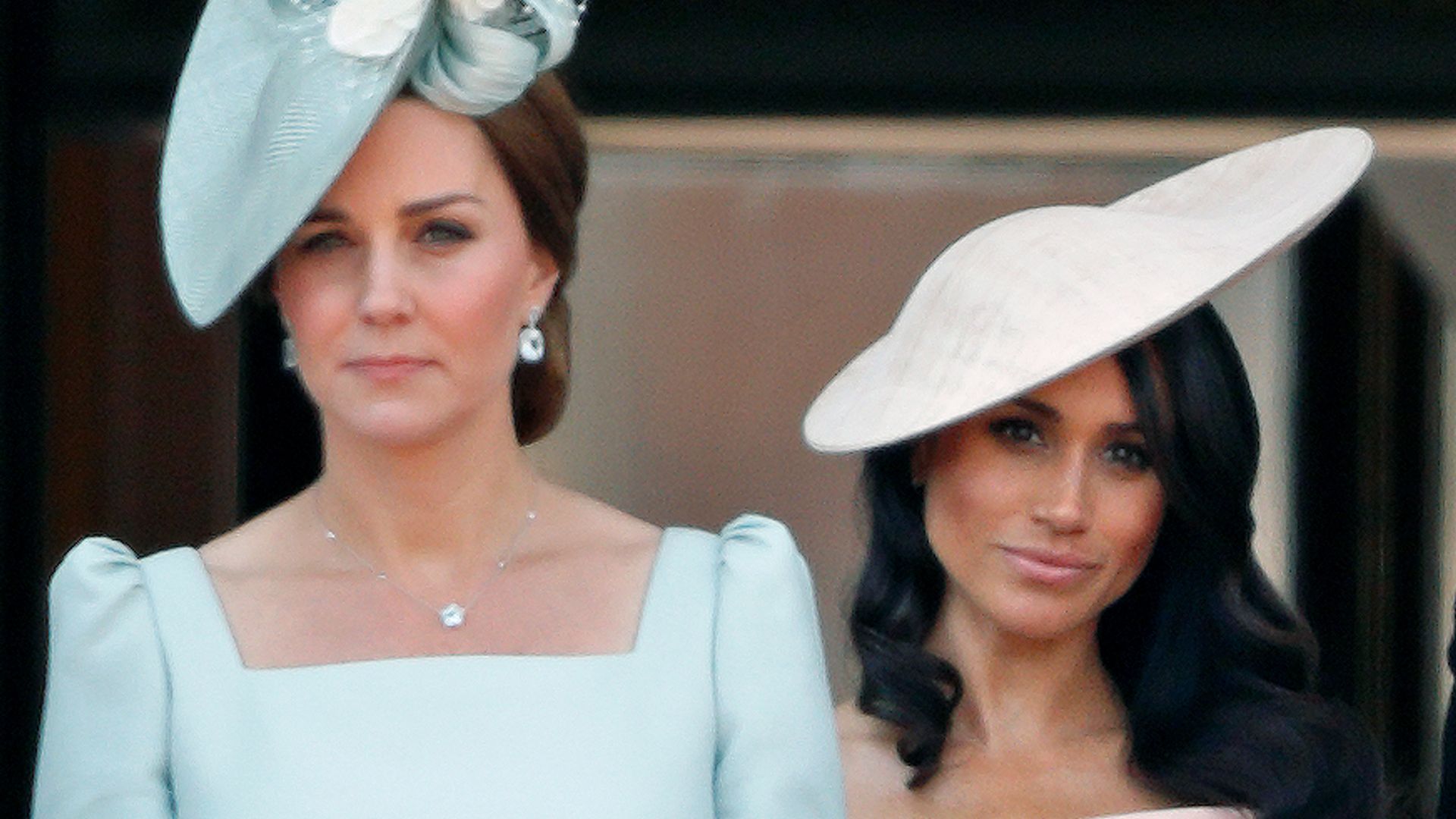 Kate Middleton in a blue dress standing in front of Meghan Markle in a pink dress at Trooping The Colour 2018