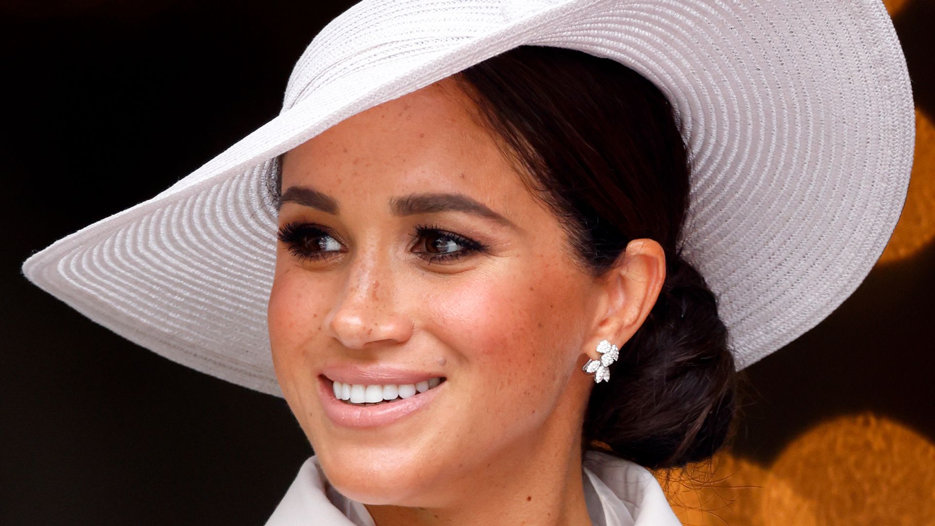 Meghan Markle in a white dress and brimmed hat