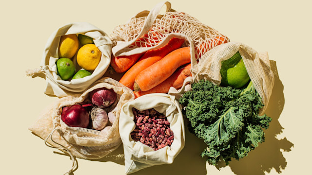 Variety Fresh of organic fruits and vegetables and healthy vegan meal ingredients in reusable eco cotton bags on beige background . Zero waste shopping concept. Healthy food, clean eating, eco friendly, no plastic. Flat lay, top view