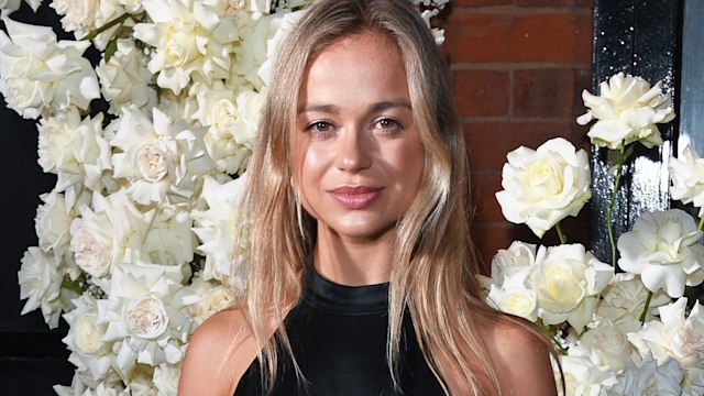 Lady Amelia Windsor in a black top and polka dot skirt in front of white flowers