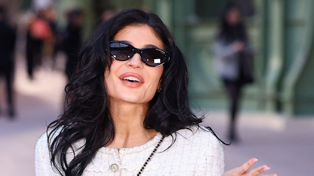 Kylie Jenner gesturing to the camera in a white suit
