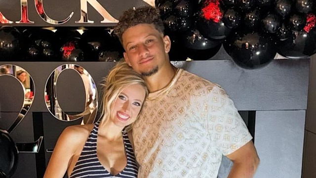 patrick and brittany mahomes leaning on each other in front of huge balloon display