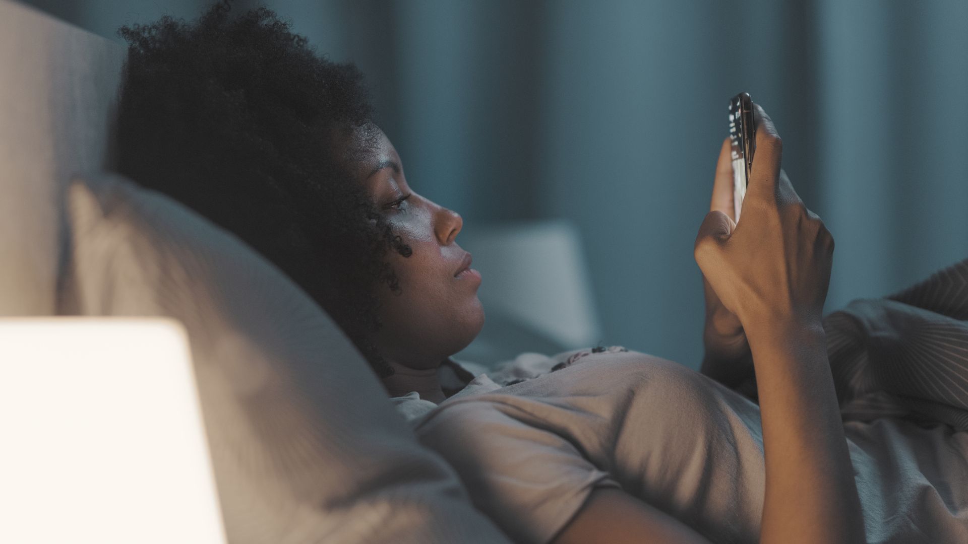 woman looking at her phone in bed at night