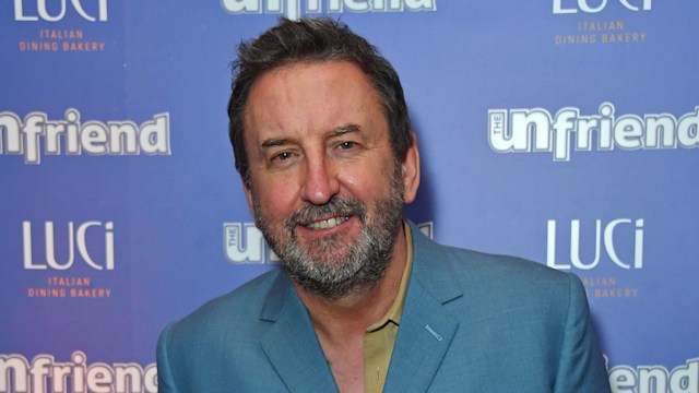 Lee Mack in blue suit smiles for cameras at press night after party for "The Unfriend" at Luci 