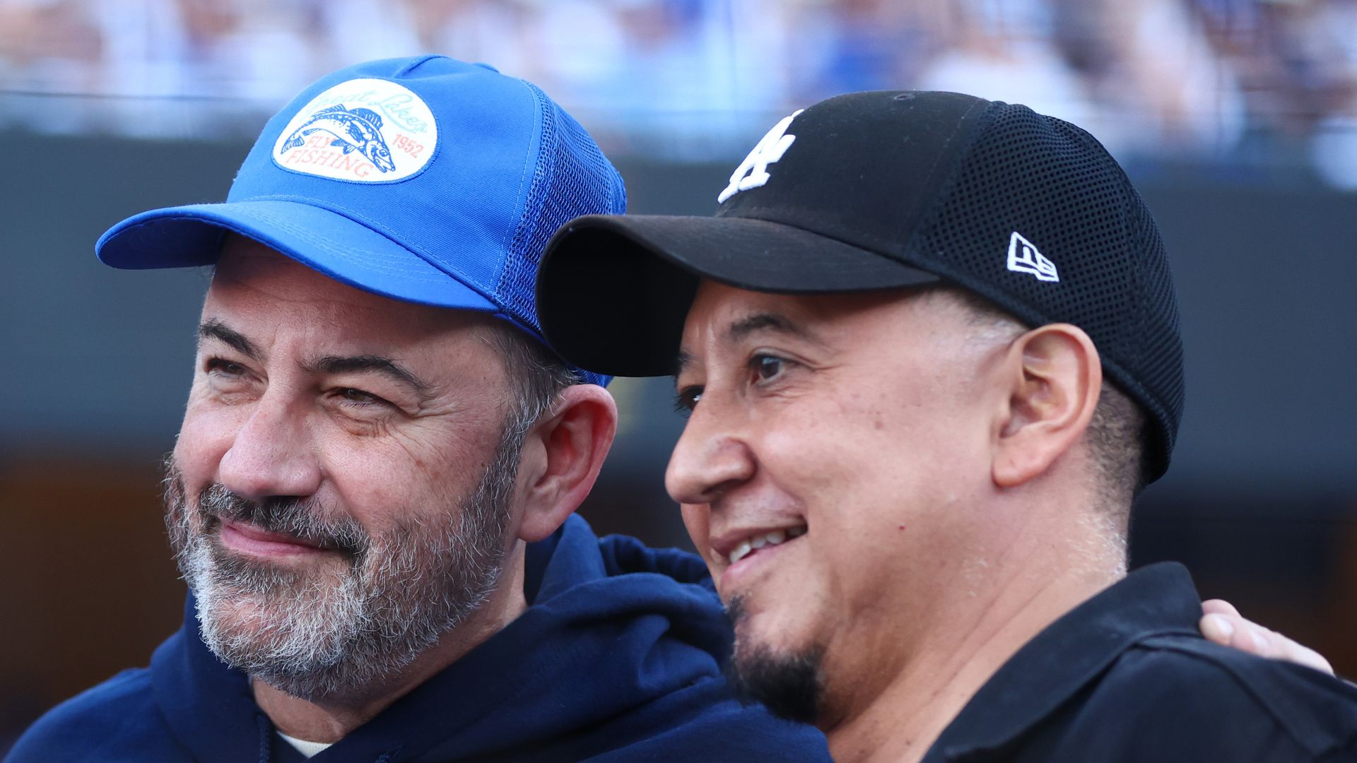 Cleto and Jimmy smile in baseball caps at a sporting event