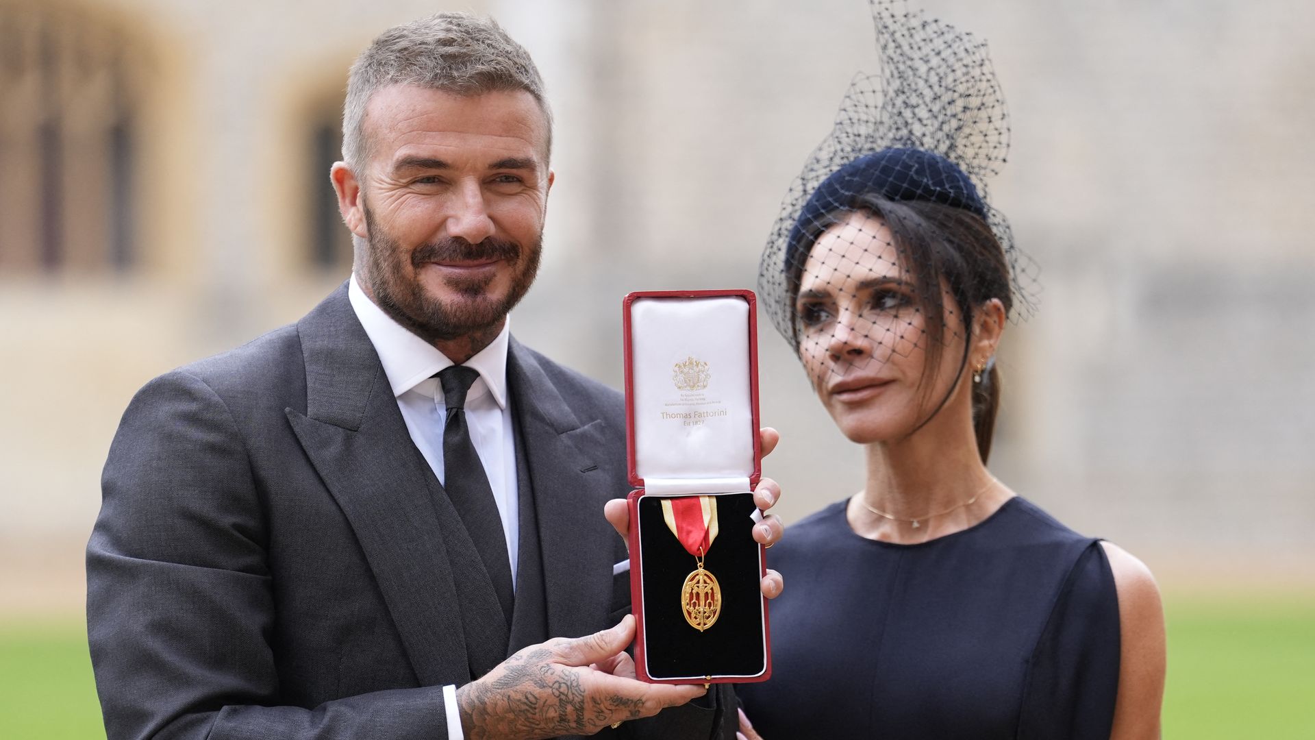 Former England footballer David Beckham (L) poses next to his wife singer and fashion designer Victoria Beckham (R) with his medal after being appointed as a Knight Bachelor (Knighthood) for services to sport and charity at an investiture ceremony at Windsor Castle on November 4, 2025. (Photo by Andrew Matthews / POOL / AFP) (Photo by ANDREW MATTHEWS/POOL/AFP via Getty Images)