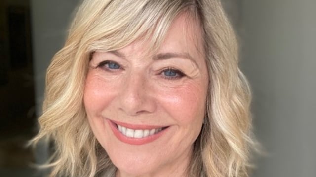 woman smiling with blonde hair wearing a sage green shirt