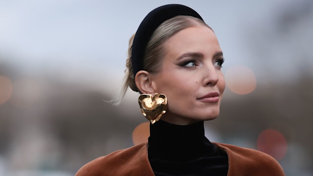 PARIS, FRANCE - JANUARY 22: Leonie Hanne seen wearing a brown Schiaparelli outfit, blazer jacket, long skirt, tights, black leather high boots and a red Schiaparelli handbag, black headband and golden earrings outside Schiaparelli Show during the Haute Couture Spring/Summer 2024 as part of  Paris Fashion Week on January 22, 2024 in Paris, France. (Photo by Jeremy Moeller/Getty Images)