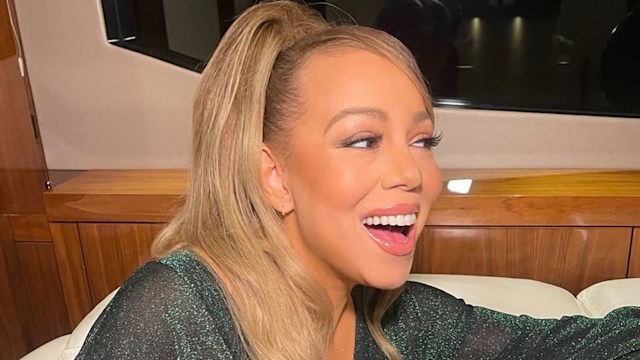 Mariah Carey smiling while wearing a green sparkly dress