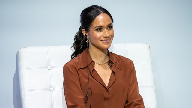 Meghan Markle wearing brown shirt sitting on speaking panel