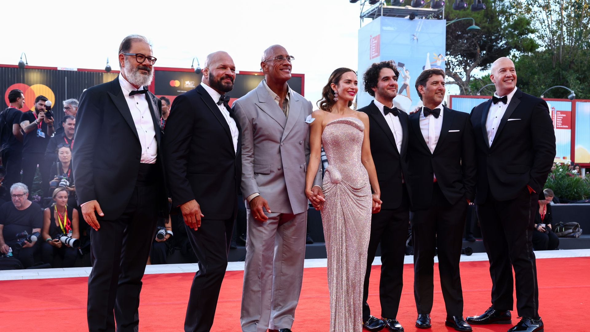 Andrea Romeo, Mark Kerr, Dwayne Johnson, Emily Blunt, Benny Safdie, David Koplan and Hiram Garcia attend "The Smashing Machine" red carpet during the 82nd Venice International Film Festival on September 01, 2025 in Venice, Italy