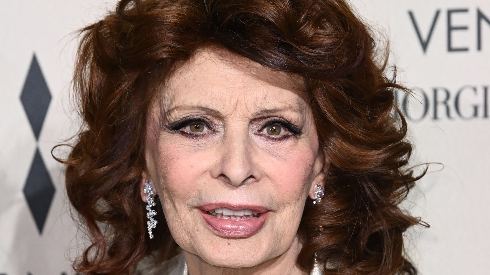 Sophia Loren wearing a white satin blazer and diamond earrings