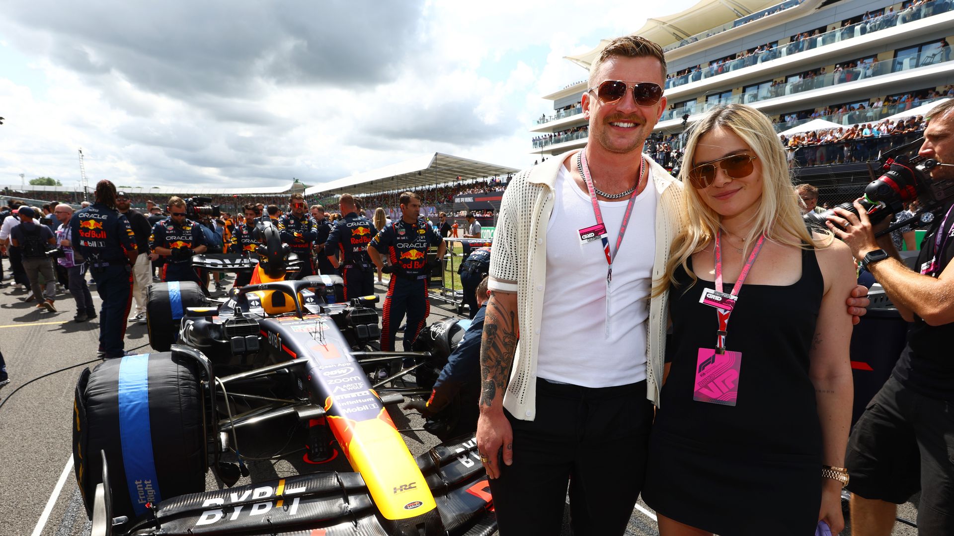 Adam Peaty and Holly Ramsay standing next to a Red Bull F1 car