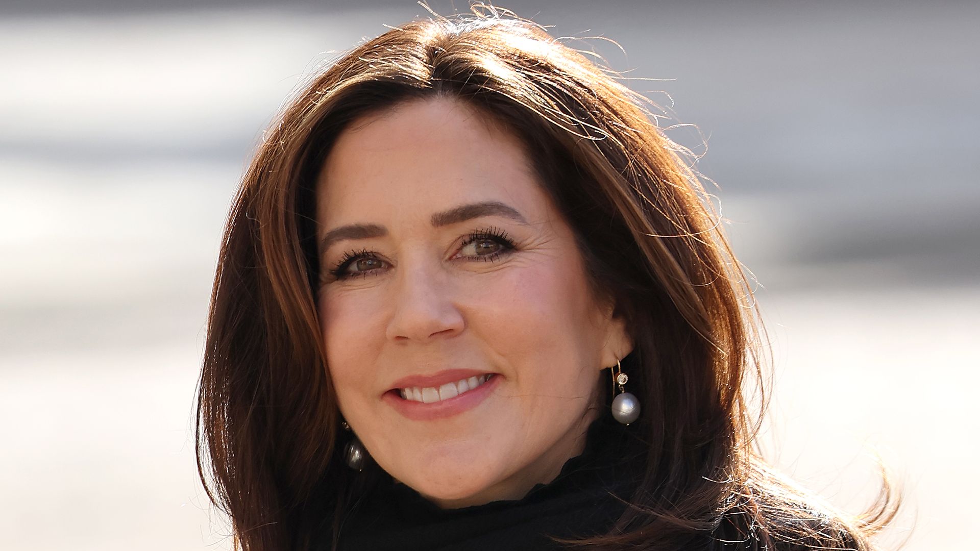 Princess Mary wearing a black scarf with a white woven coat and pearl earrings 