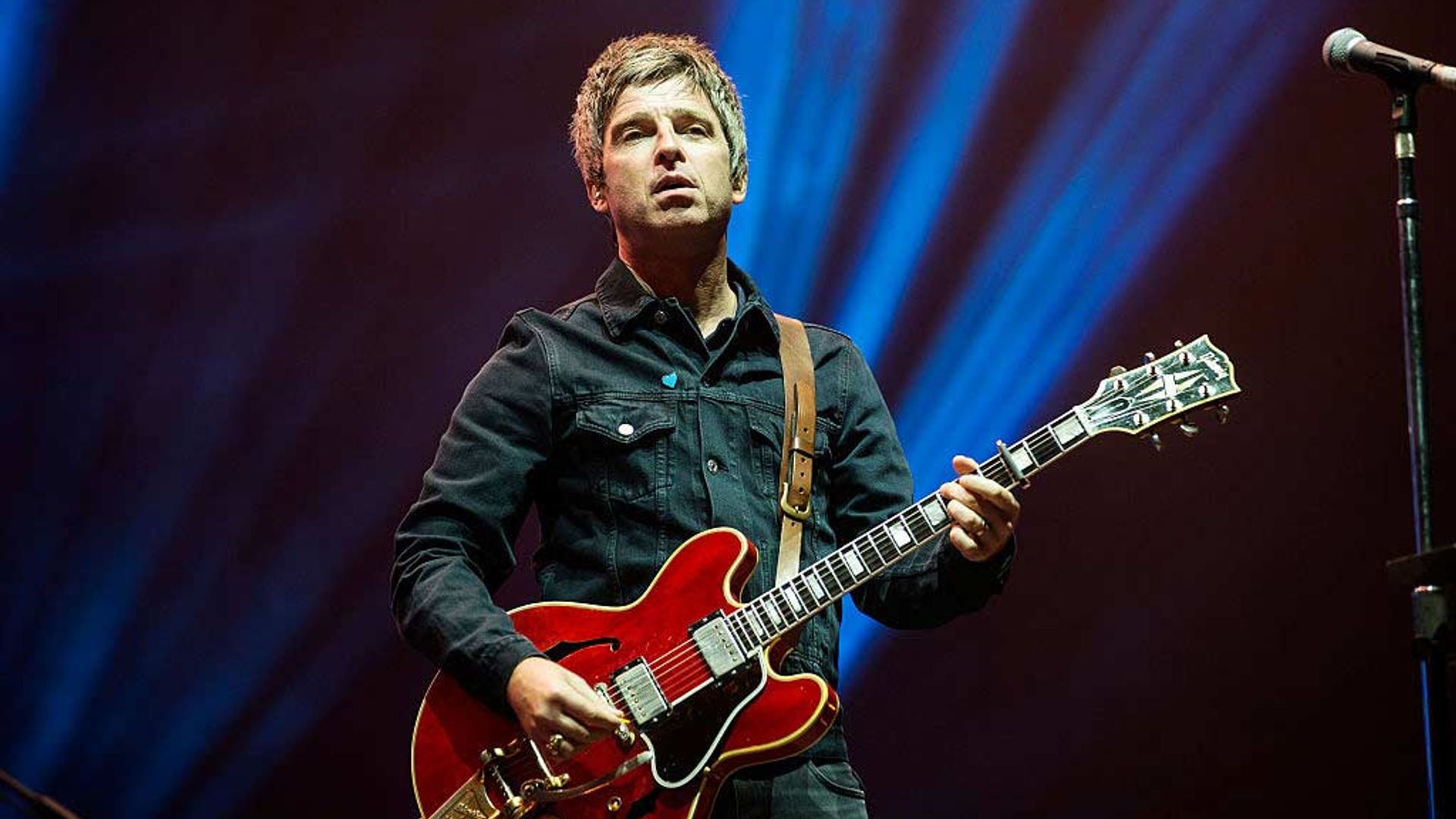 Noel Gallagher performing on stage. 