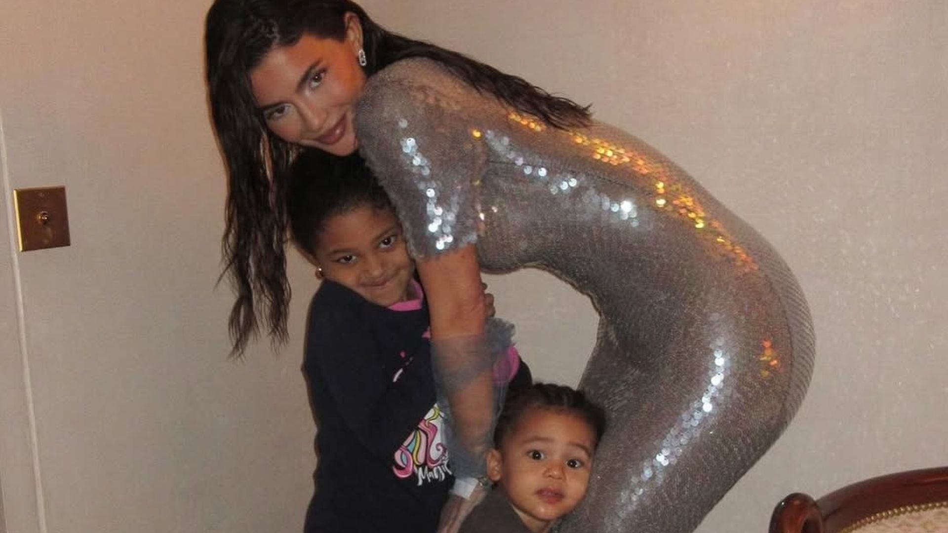 Kylie Jenner poses with her children Stormi and Aire Webster wearing a silver sequined dress, shared on Instagram by Kris Jenner