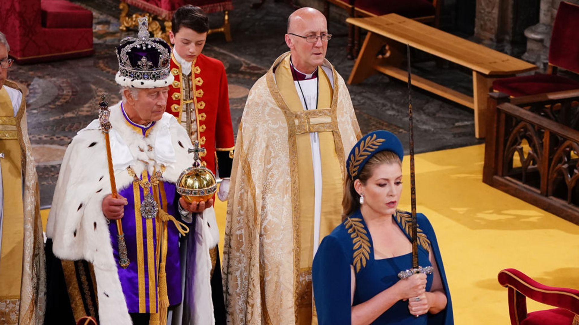 Penny Mordaunt holding the Jewelled Sword of Offering as she walks in front of King Charles