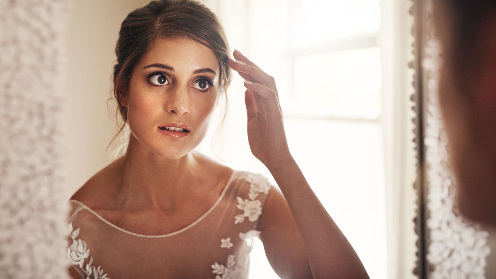 Shot of a beautiful young bride looking at herself in the mirror on her wedding day